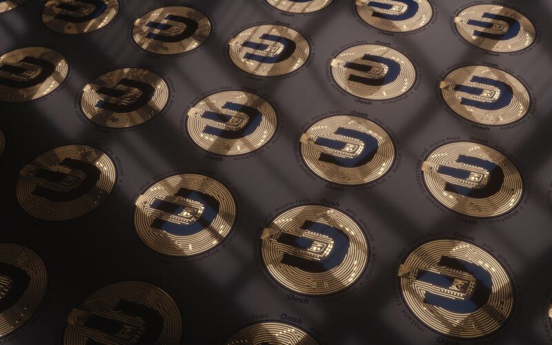 Close-up view of Dash cryptocurrency coins arranged in a pattern with dramatic lighting.